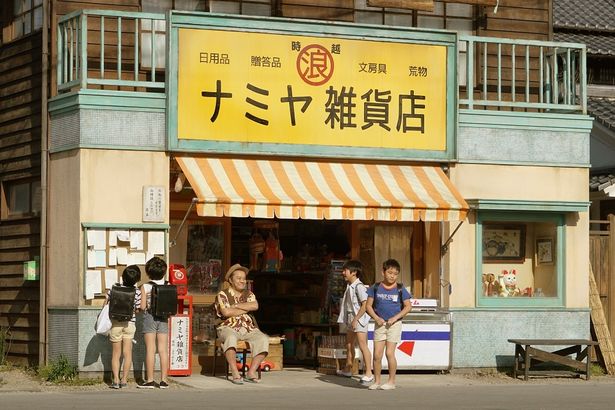 【写真を見る】“奇蹟”の鍵となる新場面カットがこちら！雑貨店の掲示板を見つめる子どもたちと店主の浪矢