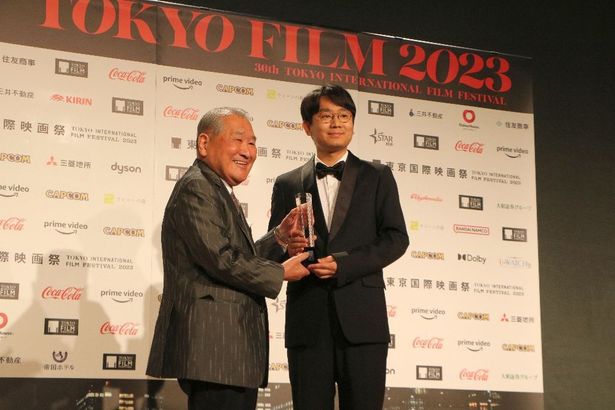 プレゼンターであるカプコン 代表取締役会長 辻本憲三氏がトロフィーを授与