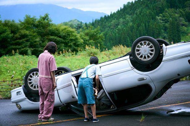 ひっくり返った車の中で座っているおじいさん