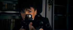 FBI 捜査官のヴェローナ(エミー・レイヴァー=ランプマン)が銃を構える姿