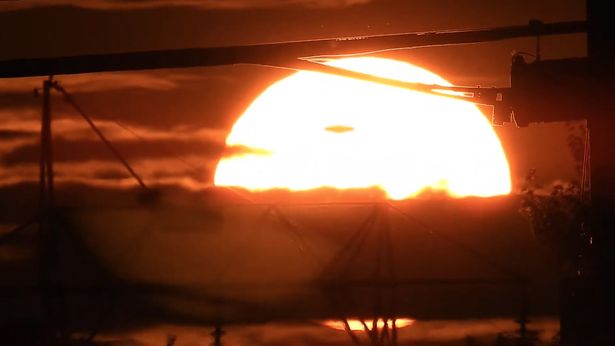 赤く燃える太陽に浮かび上がる未確認飛行物体