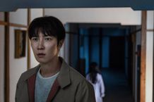 写り込んだ幽霊らしき少女の後ろ姿に気付かず神妙な面持ちをこちらに向けるヤヒロ