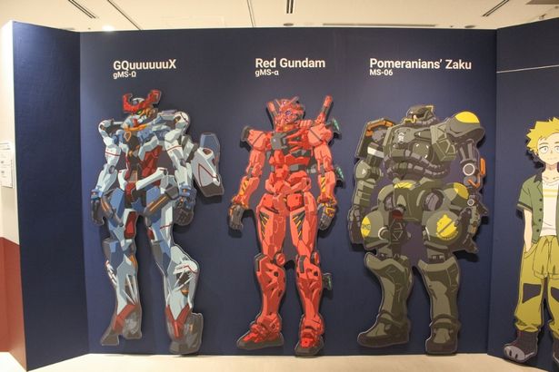 思いがけずマチュが乗ることになるジークアクス、そして街で出会った赤いガンダム。右にはポメラニアンズ仕様のザクも
