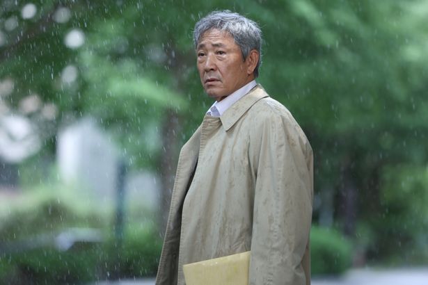 雨が降りしきる中、傘を持たずにたたずむ湯上谷弁護士