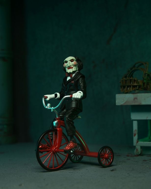 劇中さながらに三輪車をこぐビリー人形(「ソウ SAW シリーズ/ ジグソウ・キラー(レッドローブ Ver.)アルティメット 7インチ アクションフィギュア」)