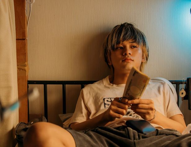 ⼤量の札束を数えながらもどこか虚な表情のタクヤ