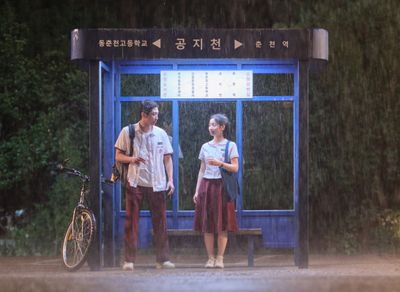 2人が距離を縮めるきっかけになったバス停での雨宿りのシーンを切りとった場面写真