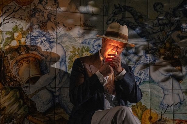 ジョン・チーヴァーが煙草を吸う背に、アウグストゥスの庭園の鮮やかな壁画が見える
