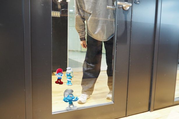 【写真を見る】スマーフが編集部のオフィスへ来社！「こんなドアはキノコ村にはないなあ…」