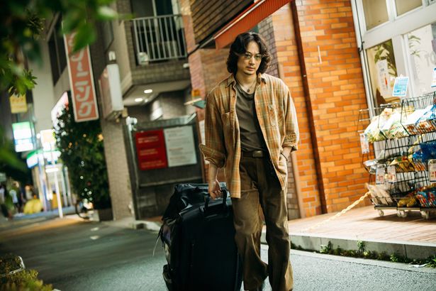 梶谷が“運び屋”の仕事のため巨大なキャリーバッグを運ぶ姿
