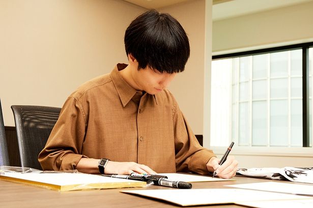 真剣な表情で色紙にメッセージを書いていく奥山監督