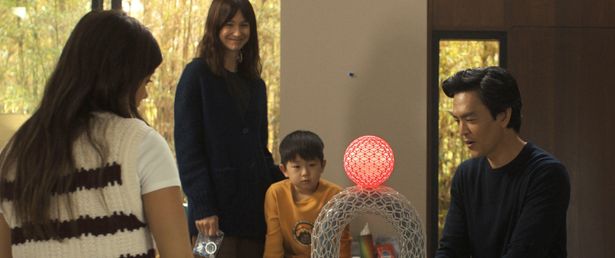 家庭⽤AI機器“アイア”が届き、期待に胸を膨らませる様子のカーティス⼀家