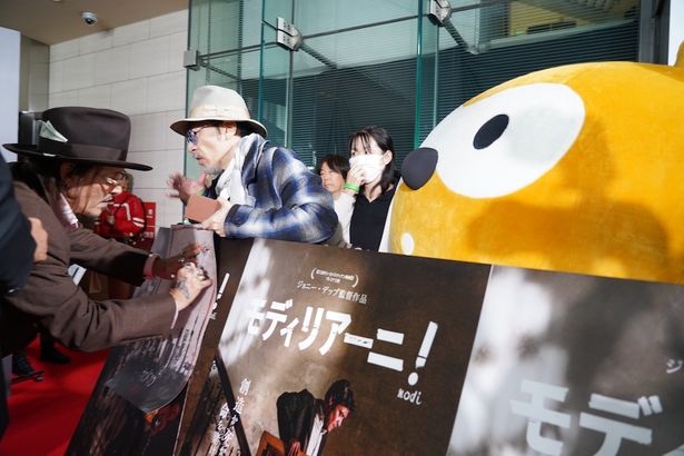 ジョニー・デップがサインをする様子を見つめるポンタ