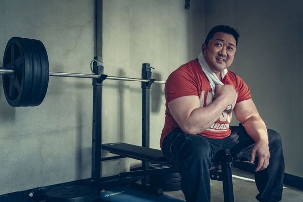 ドンソクがトレーニングマシンに腰かけ笑顔を見せる様子