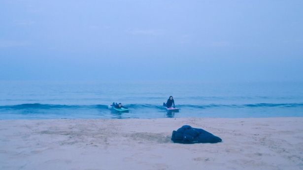冬の海でサーフィンをする2人