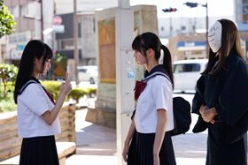 まいきち演じる皐月が撮影する美咲の後ろには、和服＆お面姿の神様が