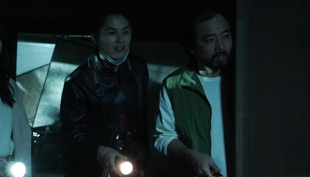 懐中電灯を片手に不安げな表情を浮かべる