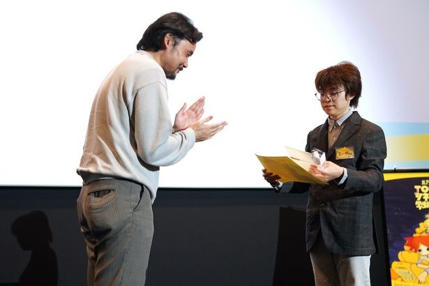 拍手を贈りながら、トロフィーと記念品を渡す岩井澤監督