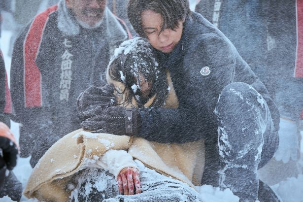 吹雪の中、悠希を必死に抱きかかえる稔