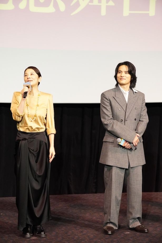 【写真を見る】小池栄子、光沢感のあるゴールドのブラウス＆ドレープが美しいブラックのスカートを合わせたエレガントなスタイルで登場