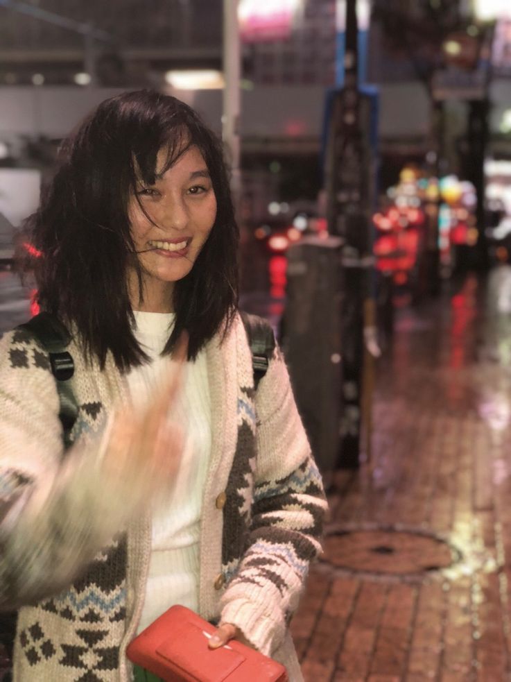 暴風雨の夜。傘が壊れ、雨に打たれながらもピースサイン