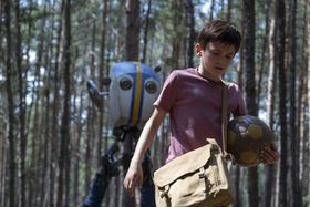 二足歩行のロボットが少年を追って歩く