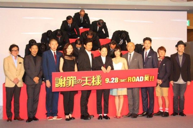 土下座をする人々をバックにフォトセッション