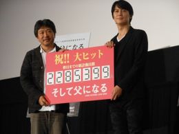 映画「そして父になる」のイベントに登場し、「累計動員数2,285,399人」と書いたフィリップを持つ主演の福山雅治(右)と是枝裕和監督(左)
