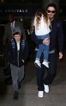 娘のハーパーを抱いて歩くデビッド・ベッカム